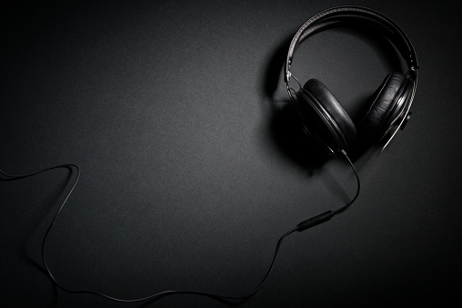 Stylish DJ headphones set on dark background from above