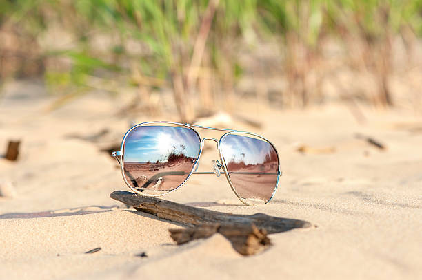 istock Trendy sunglasses lost on the beach sand. Outdoors closeup. 513475659