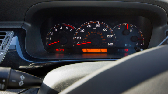 Huntingdon, United Kingdom - February 22, 2014: This is a view through the steering wheel towards the speedometer and rev counter of  Honda FR-V 6 seat people carrier. It shows the mpg in the orange sector and the indicator stalk on the left.