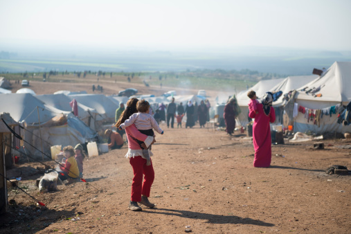 Atmeh, Syria - January 14, 2013: Syrian refugees walk outside their tents at a camp for internally displaced persons in Atmeh, Syria, adjacent to the Turkish border.