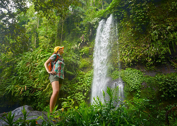 istock happy young woman backpacker looking at the waterfall in jungles 513476516