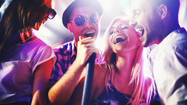 Group of people singing karaoke. stock photo