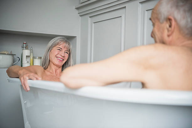 istock Senior woman smiling in bath with husband in foreground 513481784