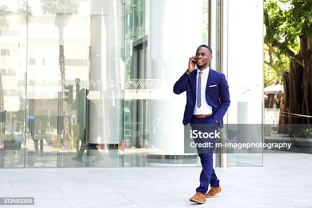 Businessman Walking In The City Using Mobile Phone Stock Photo - Download Image Now - Walking, Businessman, Men