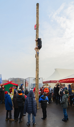 Gomel, Belarus - February 21, 2015: Young man climbs a pole for a gift during Shrovetide fun