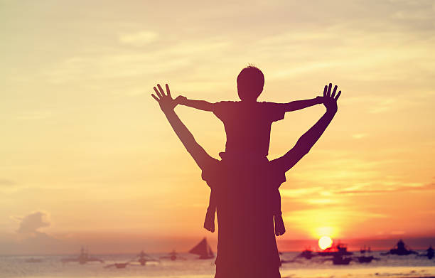 father and son on sunset beach father and son play on sunset beach on shoulders stock pictures, royalty-free photos & images