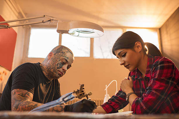 istock Pensive woman during tattooing in tattoo studio. 513489302