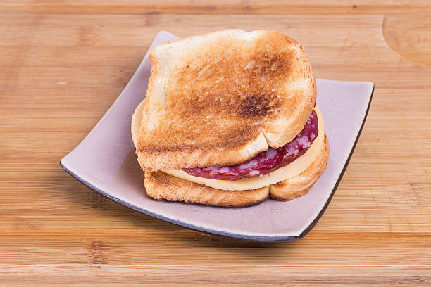 Sandwich from a toast and salami with cheese  on a grey square plate for a breakfast