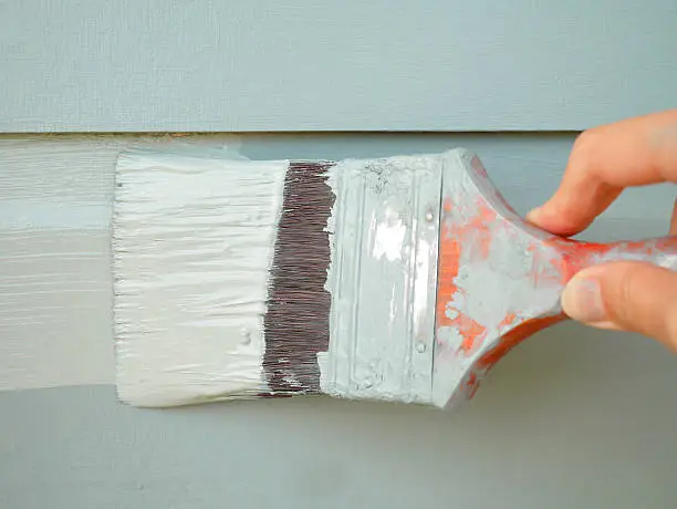 Photo of Hand holding brush painting wall