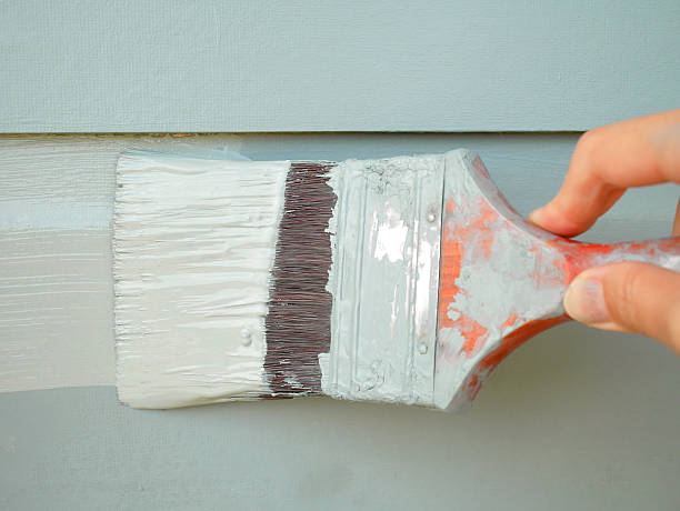 mão segurando a escova de pintura de parede - painting imagens e fotografias de stock