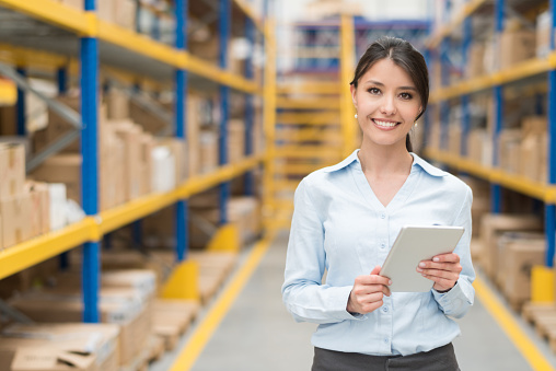 Latin American business woman doing inventory at a warehouse using a tablet computer