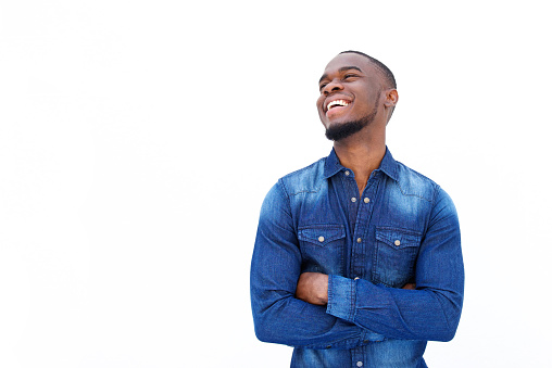 Portrait of a cheerful young african man laughing with arms crossed against white background