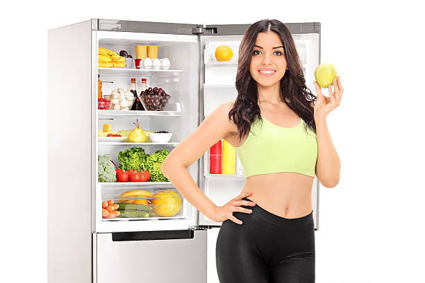 istock Woman holding an apple in front of a fridge 513501457