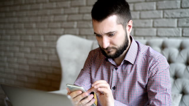 young adult bearded man with a smartphone