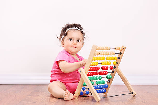 istock Little girl playing with an abacus seated on floor 513530365