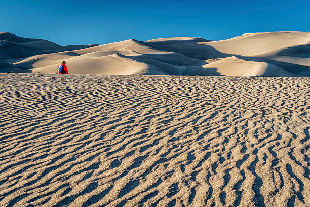 Lost in the sea of sand Lost in the sea of sand -  a lonely hiker in a dunefield in Great Sand Dunes National Park, Colorado great sand dunes national park stock pictures, royalty-free photos & images