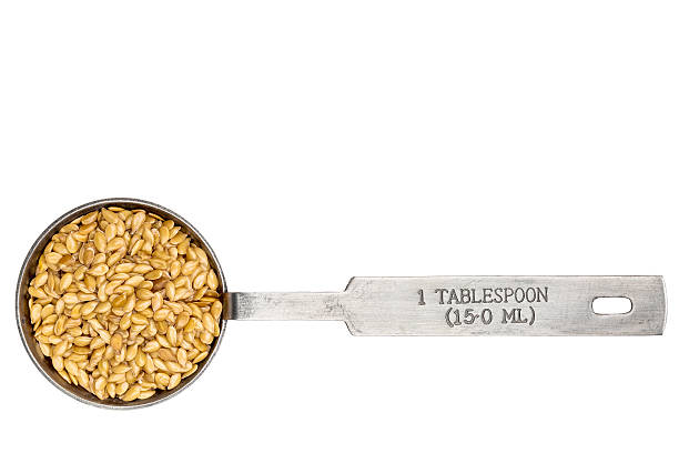 golden flax seeds in a metal measuring tablespoon isolated on white