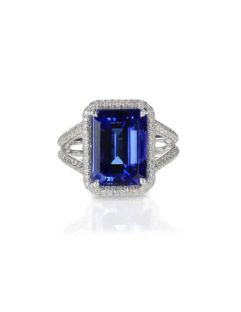 Large emerald cut sapphire  blue  engagement cocktail fashion ring with halo setting and pave diamonds isolated on white with a reflection