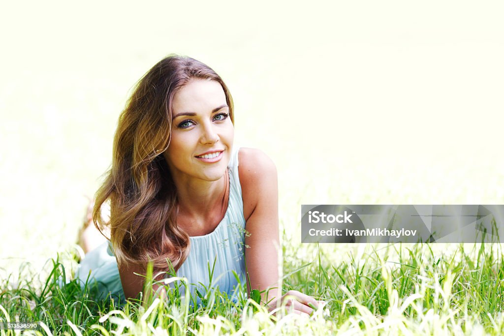 young woman in blue dress lying on grass beautiful young woman in blue dress lying on grass Adult Stock Photo