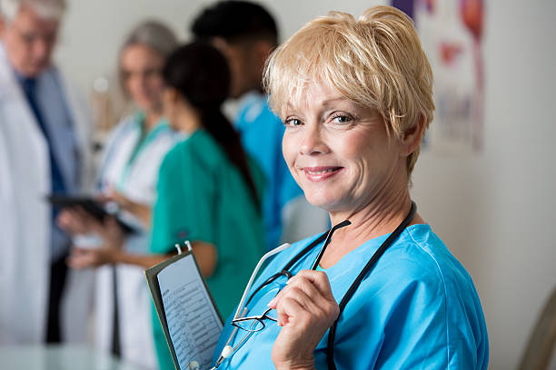 zuversichtlich älterer krankenschwester im krankenhaus personal treffen - board room senior adult clothing smiling stock-fotos und bilder