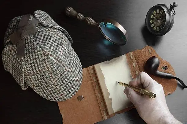 Adult Male Hand With Fountain Golden Pen, Open Vintage Notebook With Blank Brown Page, Sherlock Or Deerstalker Hat, Magnifier, Clock On Black Table Background