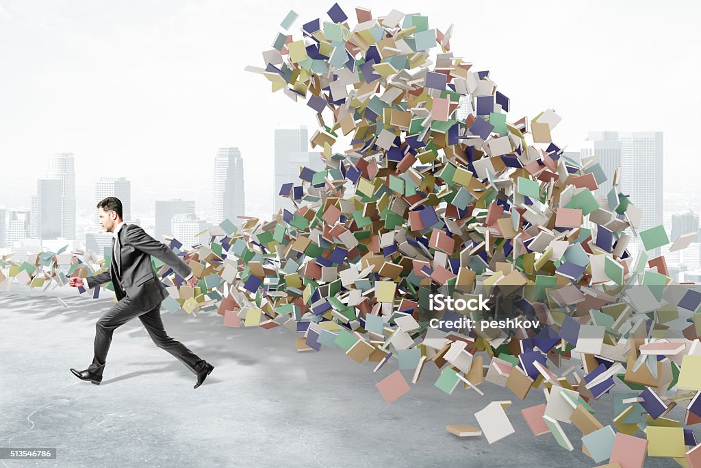 Education concept with businessman runs from the mountain of boo Education concept with businessman runs from the mountain of books at city background Excess Stock Photo