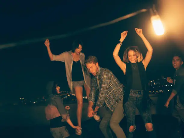 Photo of Teenager friends dancing and laughing on a rooftop party