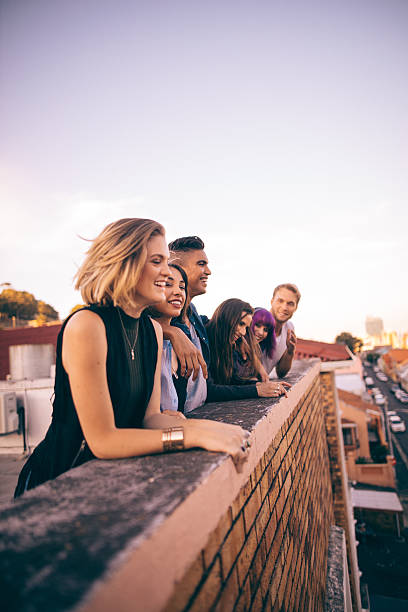 eine gruppe von freunden, auf einer sommer-party auf dem dach ein sonnenuntergang - teenager city life laughing group of people stock-fotos und bilder