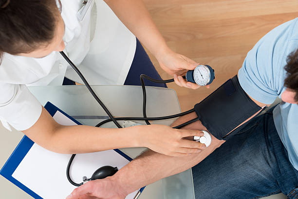 врач измеряет артериальное давление пациента мужского пола - patient blood pressure gauge doctor male стоковые фото и изображения