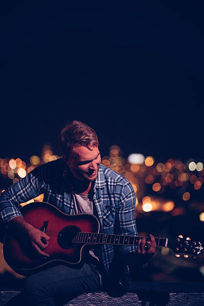 szczęśliwy nastoletnich gitarzysta gra na zewnątrz na dachu - playing an instrument vertical blurred motion outdoors zdjęcia i obrazy z banku zdjęć