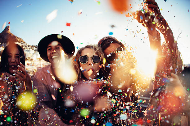 teenager hipster friends partying by blowing colorful confetti from hands - lachen fotos stockfoto's en -beelden