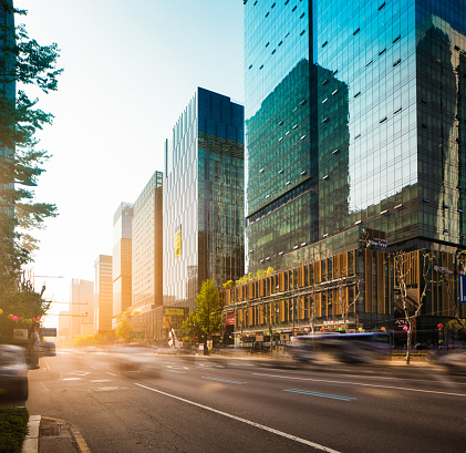 Seoul Jong-ro street at sunset with fast passing traffic and a row of tall office buildings.