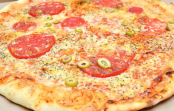 Close up photo of fresh ham and cheese pizza with olives and tomatos