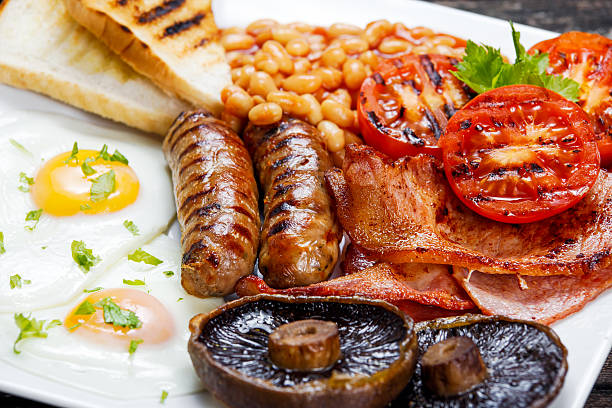 café da manhã inglês completo com bacon, linguiça, ovo, feijão e cogumelos - fry up - fotografias e filmes do acervo
