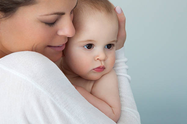 Mother Holding Tight Her Baby Boy On Blue Background stock photo