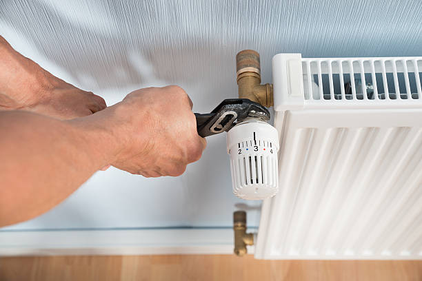 istock Plumber Fixing Radiator With Wrench 513554020