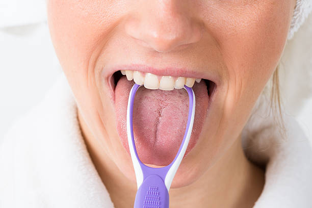 Woman Using Tongue Cleaner Close-up Of A Woman Cleaning Her Tongue tongue scraper stock pictures, royalty-free photos & images
