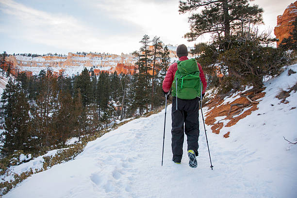 Backpacker walking on snowy footpath exploring the Canyon Rim in Bryce National Park, Utah