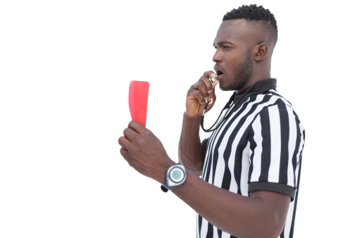 Serious referee showing red card on white background