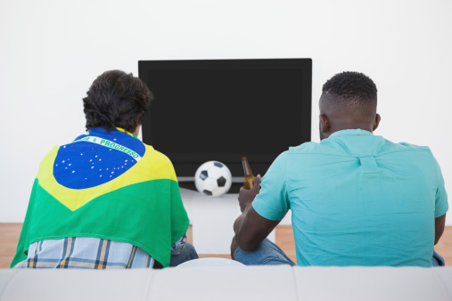 Rear view of two Brazilian soccer fans watching tv