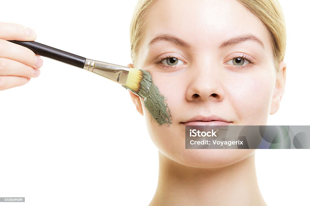 Skin care. Woman applying clay mud mask on face. Skin care. Woman applying with brush clay mud mask on face isolated. Girl taking care of dry complexion. Beauty treatment. Adult Stock Photo