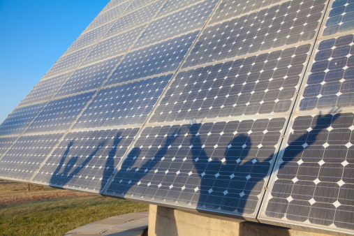 Shadows of Businesspeople with Arms Outstretched in front of Solar Panel