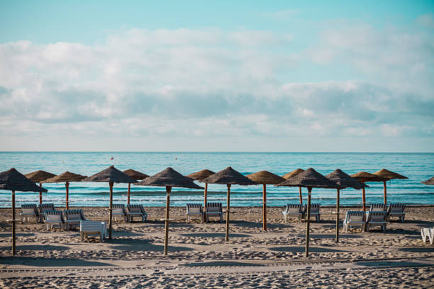 Beach in  Benicassim, Castellon, Spain with parasols and deck chairs on a cloudy summer day