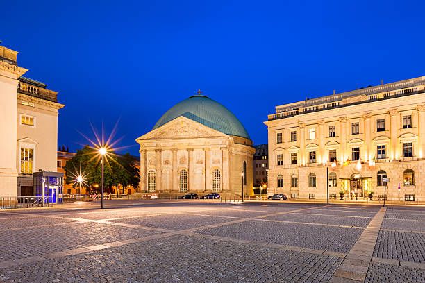 Photo of Bebelplatz with St. Hedwig's Cathedral in Berlin, Germany, illuminated at twilight blue hour. St. Hedwig's Cathedral is the seat of the Roman Catholic archbishop of Berlin.