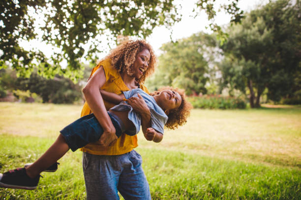 hermosa rubia de pelo rizado madre juega con ella encantadores bab - family grass toddler african descent fotografías e imágenes de stock