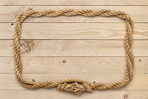 istock Rope frame on weathered light brown wooden board 513585098