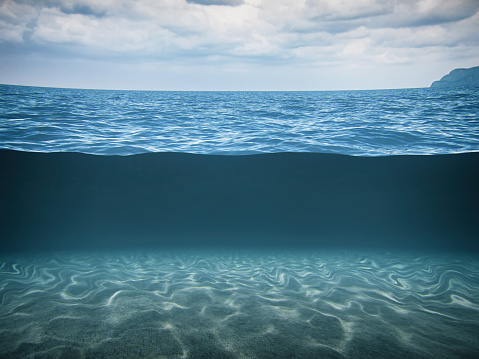 Conceptual split-shot of the deep blue sea with seabed and dark stormy sky.