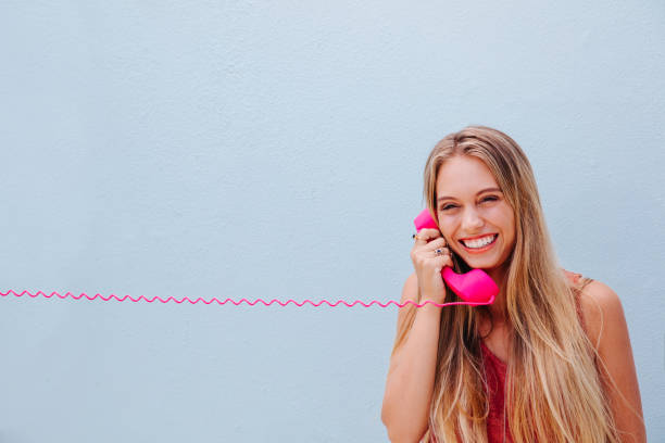 Smiling girl on vintage telephone Teenage girl in love speaking with her boyfriend on the phone, isolated on blue wall background girl flex stock pictures, royalty-free photos & images