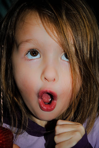 istock Girl makes silly face holding a strawberry 513586456