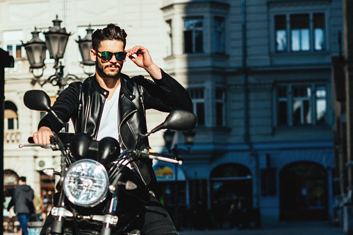 Handsome stylish man posing on a motorcycle in the city.